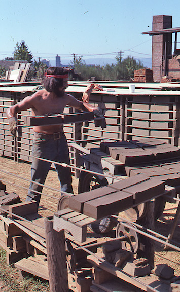 View of a worker removing the wet bricks off of the cable conveyor.