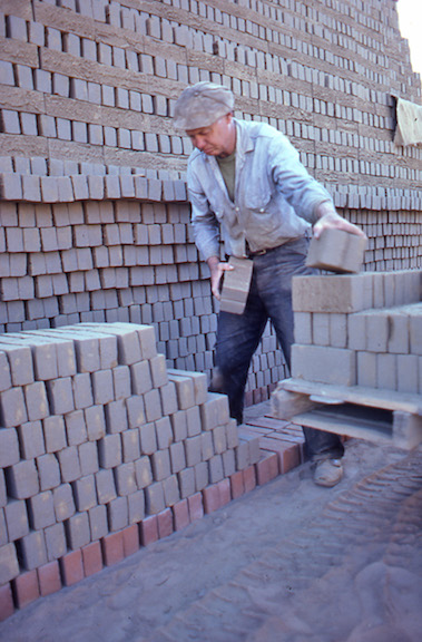 View of a worker stacking bricks at the field kiln.