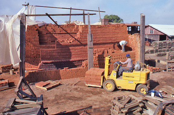 View of workers removing fired brick from the field kiln. 