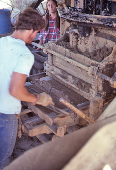 View of the worker striking off the loaded brick mold.